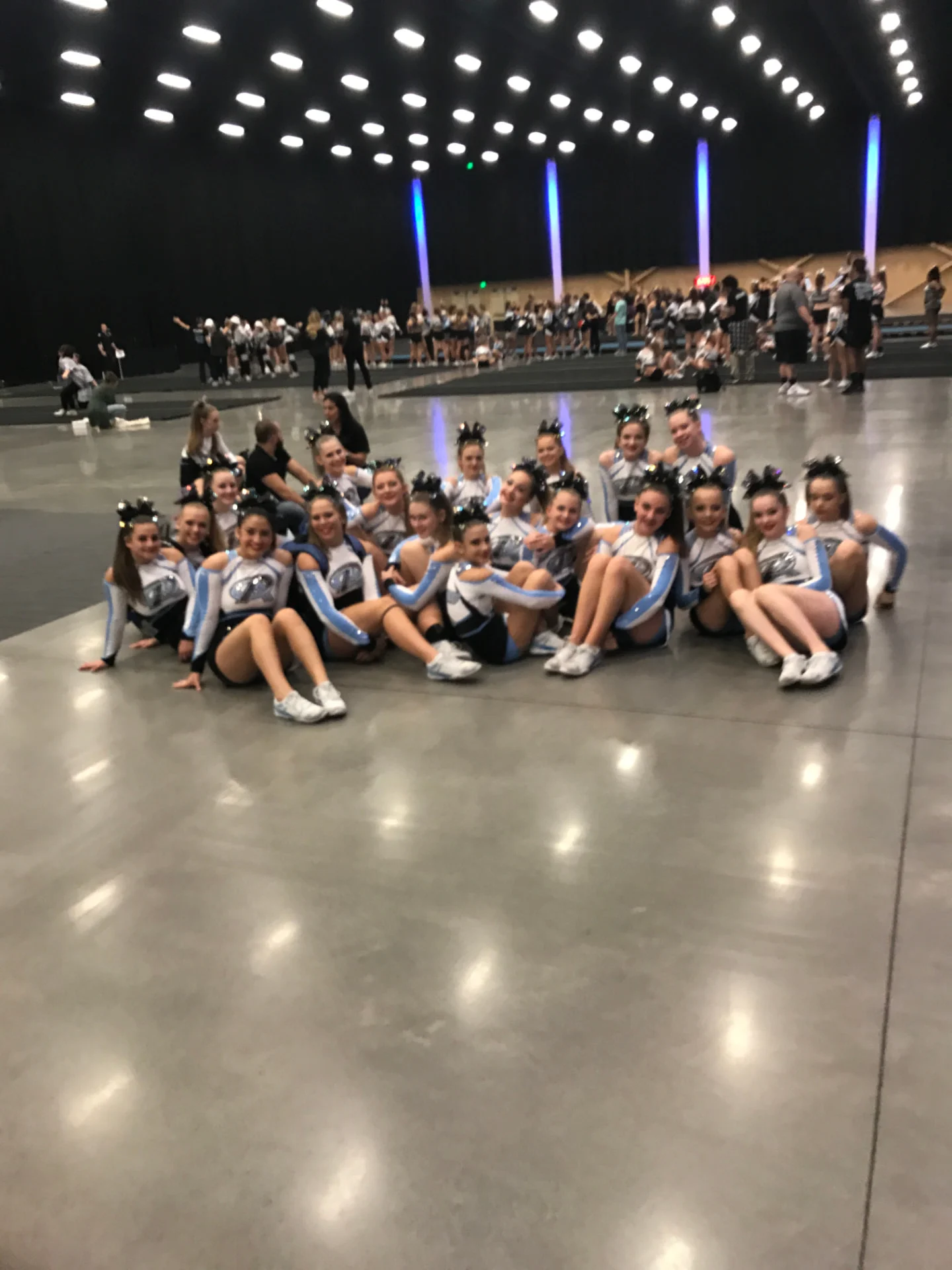 Senior cheer team seated together at a competition venue